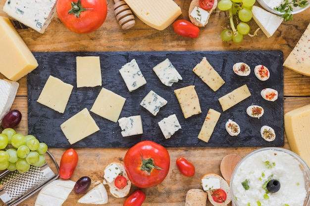 Platter of cheese slice on black slate board over the table