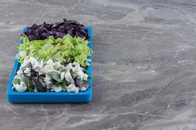 Platter of chopped cabbage, cauliflower and amaranth on marble surface