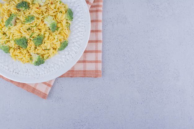 Free photo platter of cooked brown rice with broccoli topping on marble background.