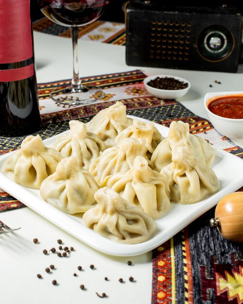 A platter of georgian khinkali served with spicy sauce