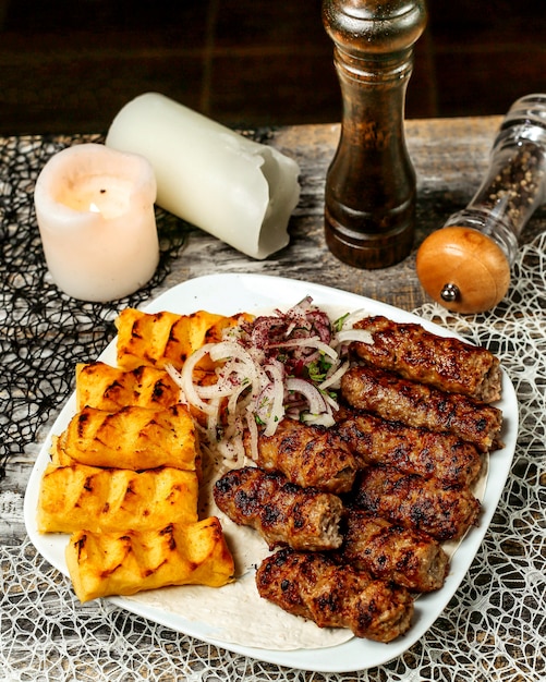 Platter of lula and potato kebab garnished with onion and sumac