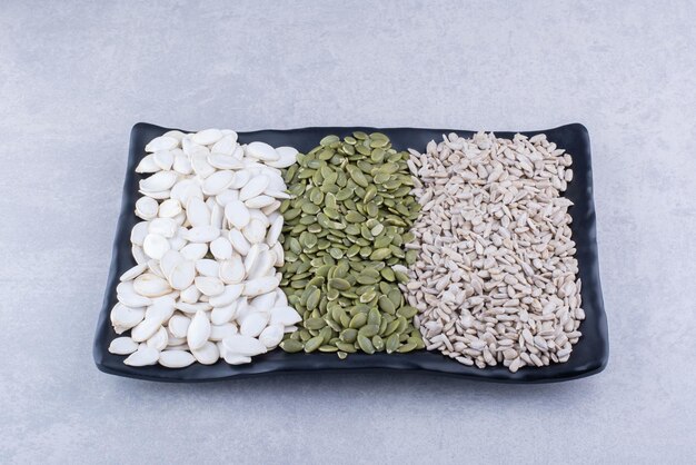 Platter of pepitas, sunflower seeds and white pumpkin seeds on marble surface