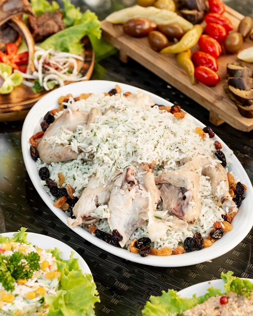 Platter of rice with dill served with chicken wings and dried fruits