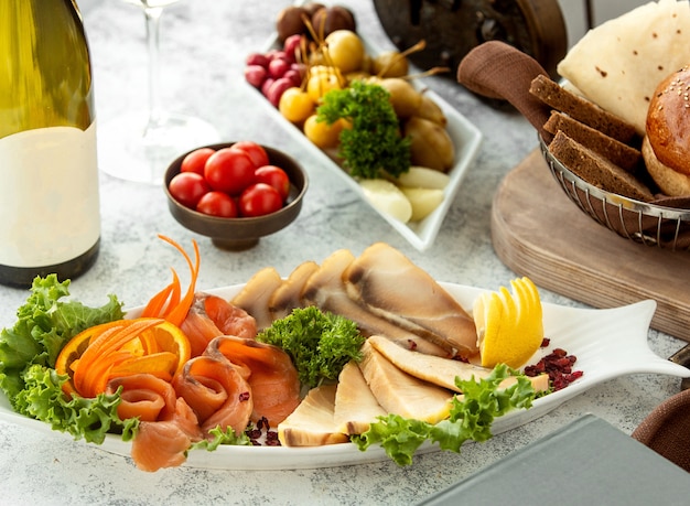 Platter of smoked meat and salmon served with carrot and lemon