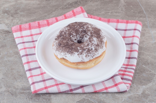 A platter with a donut on a towel on marble