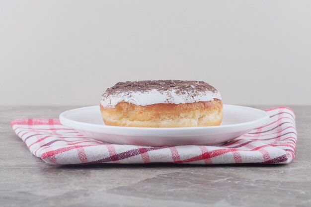 A platter with a donut on a towel on marble