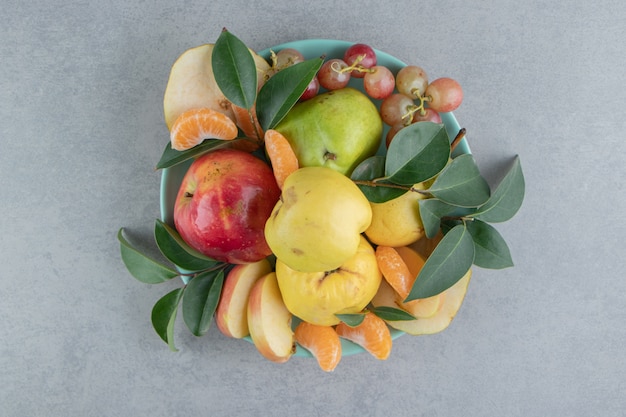 A platter with a pile of assorted fruits on marble 