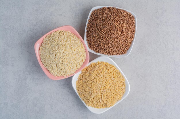 Platters of rice and buckwheat on marble surface