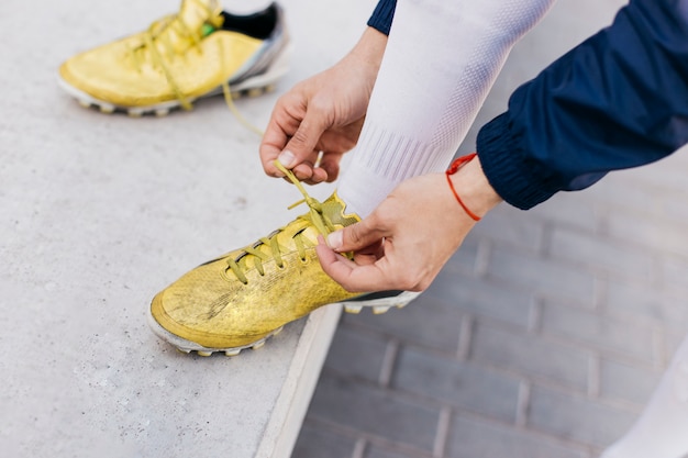 Foto gratuita giocatore che lega scarpe da calcio