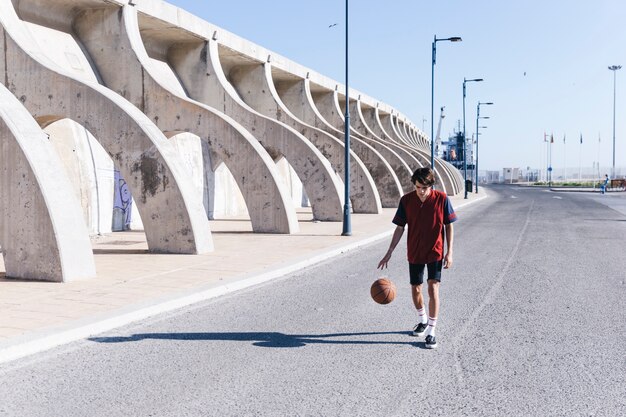 Player practicing basketball on road in city