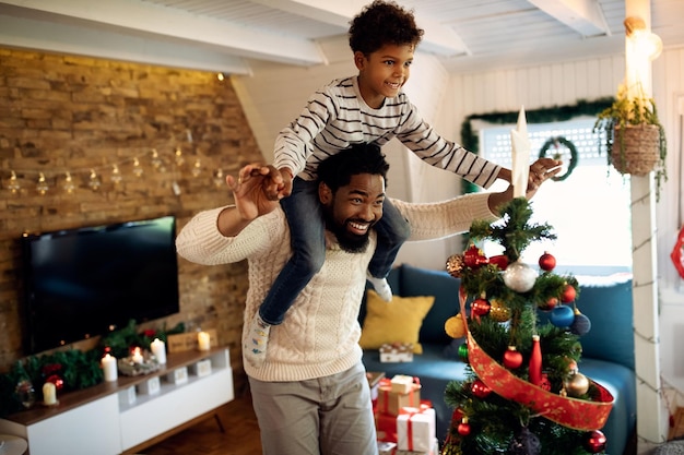 Playful African American father and son having fun on Christmas at home