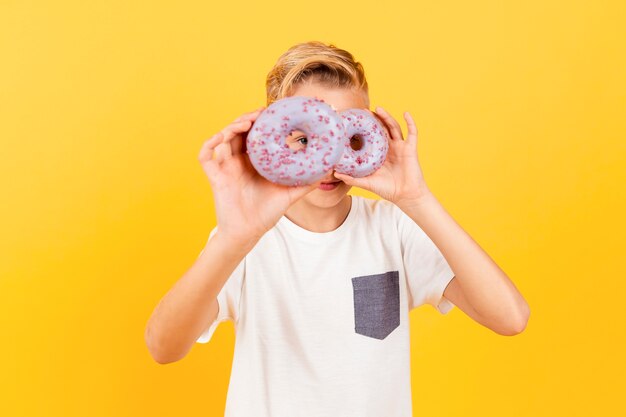 Playful boy holding doughnuts