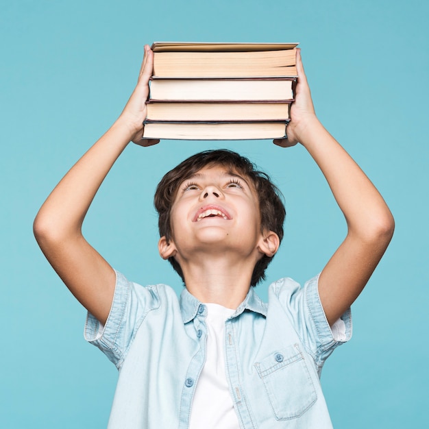 Playful boy holding stack of books