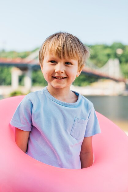 Playful boy standing with swimming ring on shore