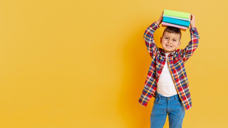 Free Photo playful boy with stack of books on his head