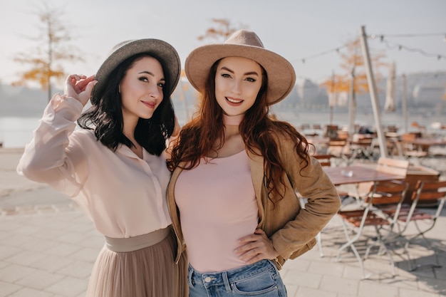 Playful brunette woman in long skirt smiling with ginger sister