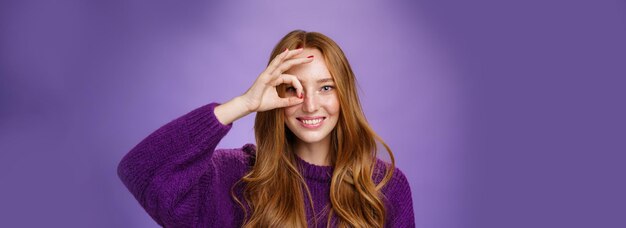 遊び心のある屈託のないカリスマ的な赤毛の女性で、そばかすがあり、長い髪が大丈夫またはゼロのジェスチャーを示しています