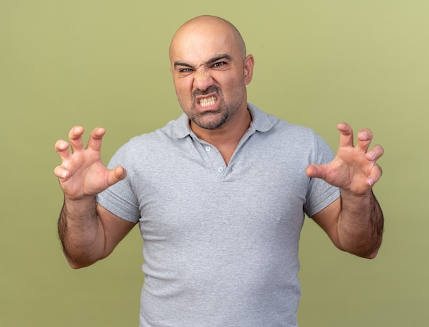 Playful casual middle-aged man doing tiger roar and paws gesture isolated on olive green wall