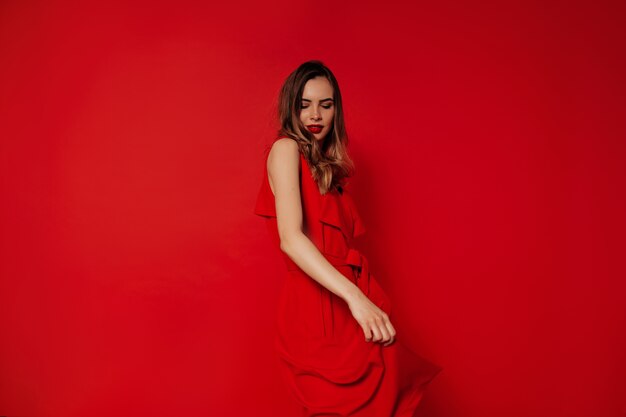 Playful charming lady wearing red dress dancing and having fun