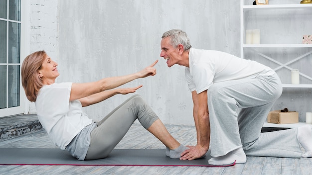 Playful couple doing yoga exercise at home