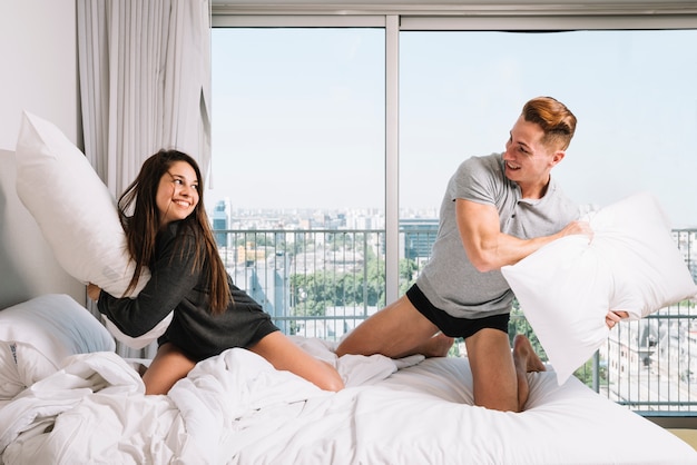 Playful couple fighting with pillows
