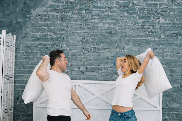 Free photo playful couple having pillow fight in home