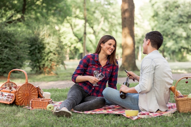 Free photo playful couple lying on a blanket with wine glasses