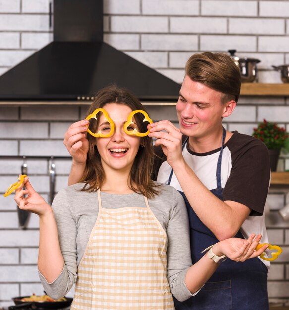 Playful couple making glasses from pepper slices 