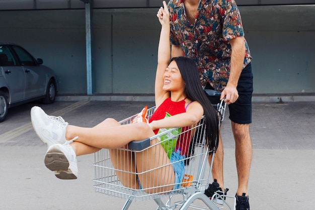 Playful couple riding in shopping trolley