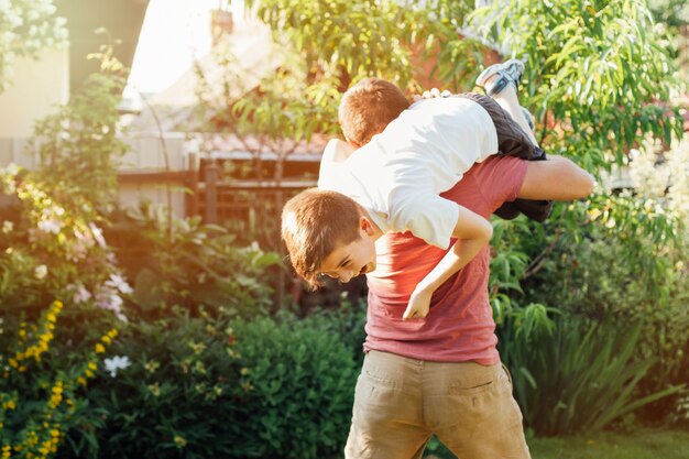 Playful father carrying his smiling son on shoulder in park