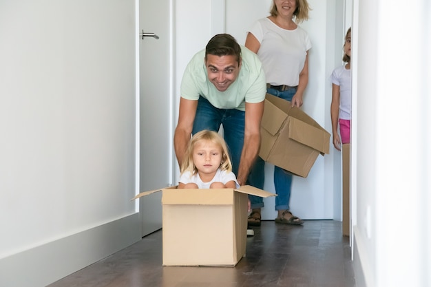 Free photo playful father pushing carton box with cute girl inside