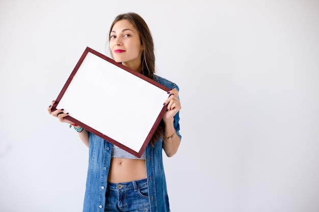 Playful girl hold a blank white placard or poster