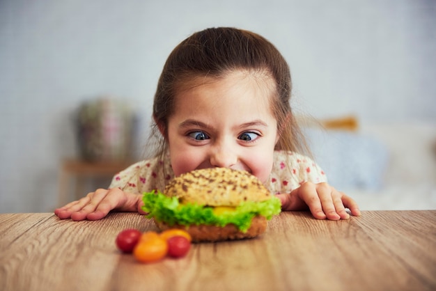 Playful girl looking at delicious hamburger