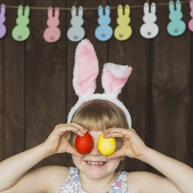 Foto gratuita ragazza allegra che posa con le uova colorate