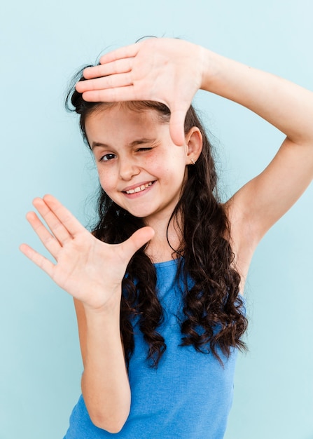 Foto gratuita ragazza allegra che mostra forma della macchina fotografica con le mani