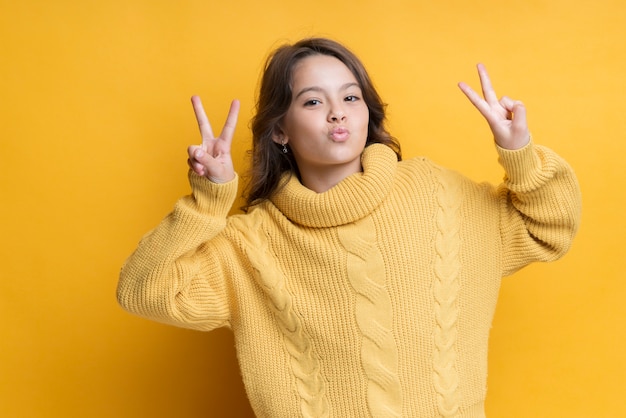 Free photo playful girl showing peace sign portrait