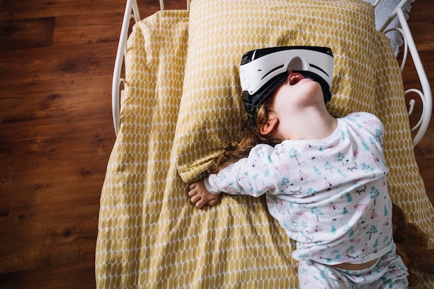 Игривая девушка в очках VR на кровати