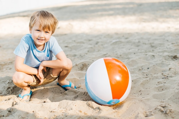 Playful kid sitting next to wind ball