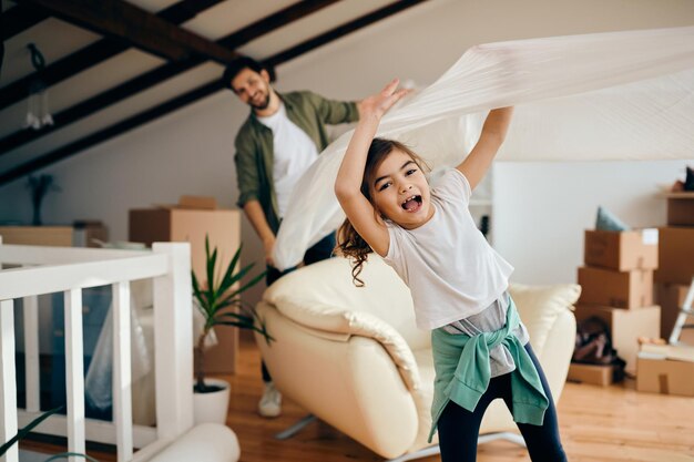 Playful little girl having fun with her father at their new home