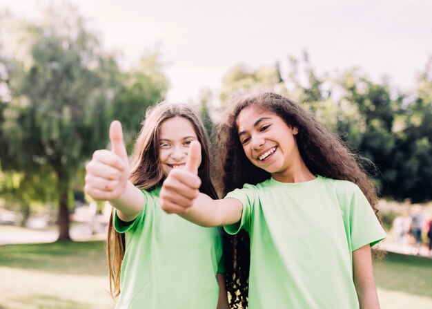 Playful little girls gesturing thumb up sign