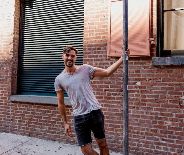 Playful man holding by a metal pole