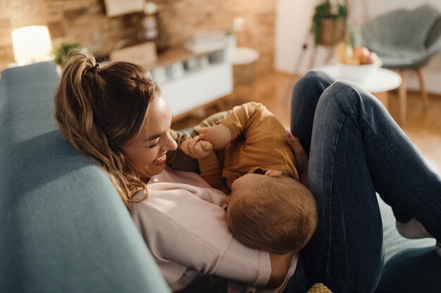 Playful mother having fun with her small son at home