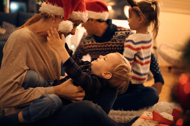 Playful mother and son having fun on Christmas eve at home