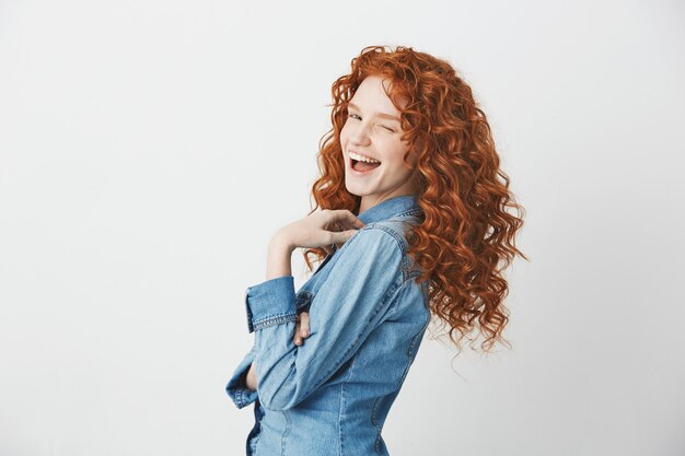 Playful redhead girl smiling winking standing in profile .