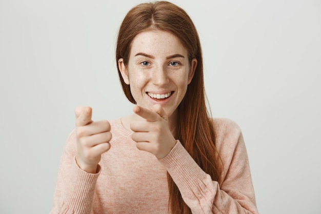 Playful smiling redhead girl pointing fingers, congratulate you