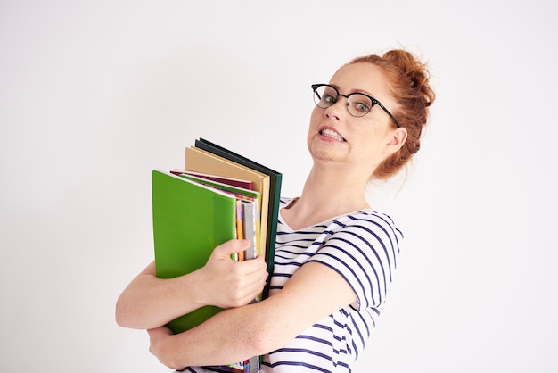 Studente giocoso con una pila di libri pesanti sparati