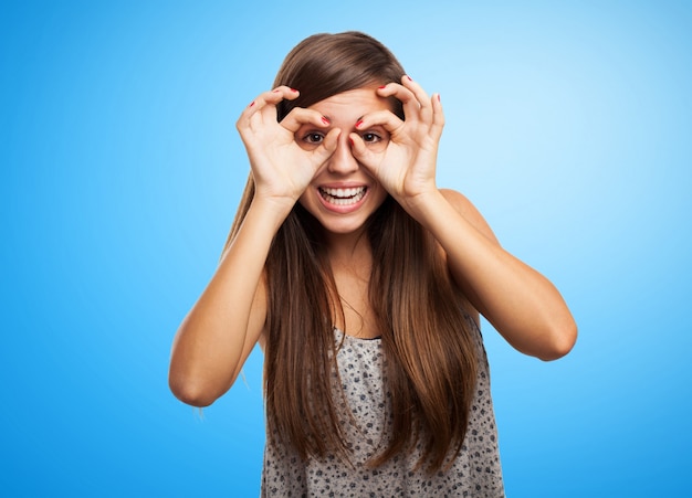 Foto gratuita studente allegra con gli occhiali gesto su sfondo blu