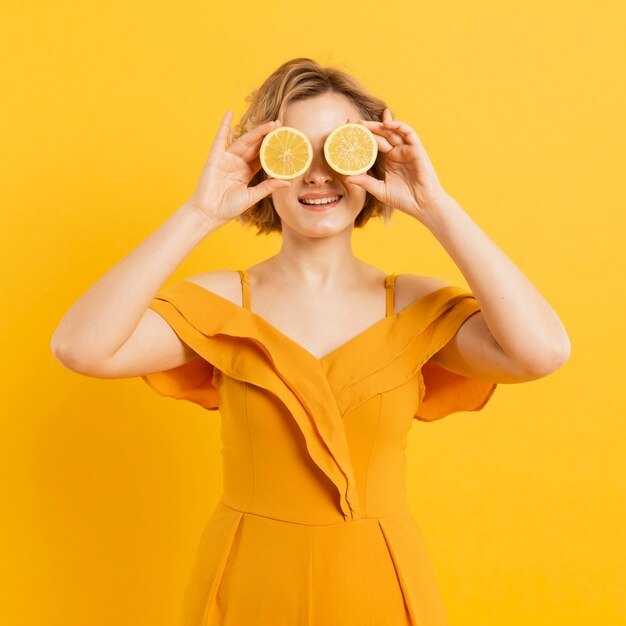 Playful woman covering eyes with lemon slices