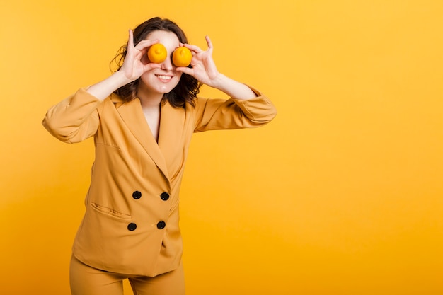 Игривая женщина закрывает глаза лимонами