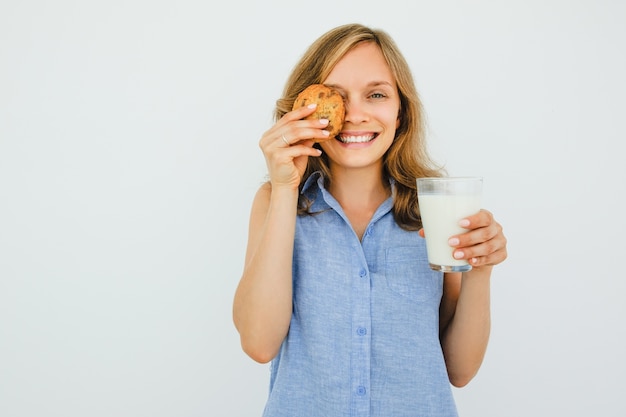 ミルクとクッキーのガラスを持つ遊び心のある女性